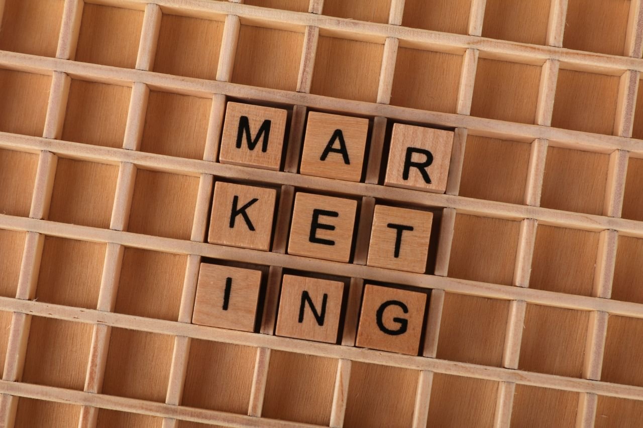 Home Wooden letter tiles spell out the word marketing on a grid background, showcasing creativity and business concept.
