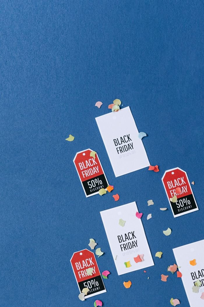 Home Colorful sale tags and confetti on a textured blue surface for Black Friday deals.
