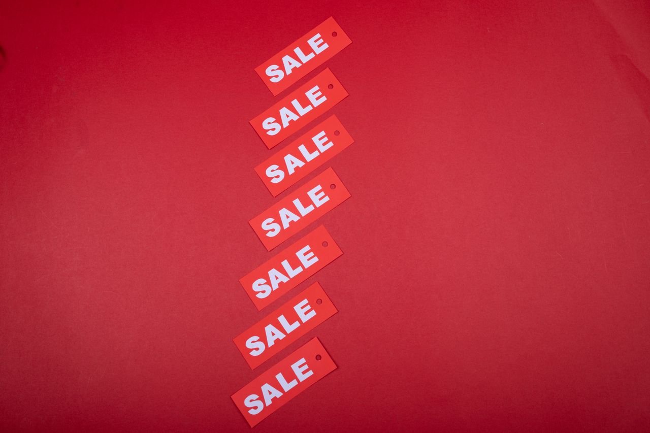 Home Top view of red sale tags arranged on a vibrant red background for commercial use.